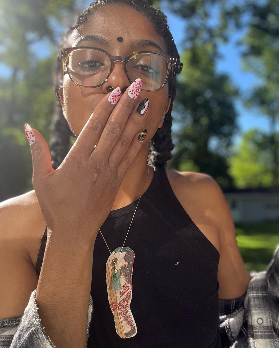 A black woman with two braids, glasses and a bindi with her hand over her mouth.